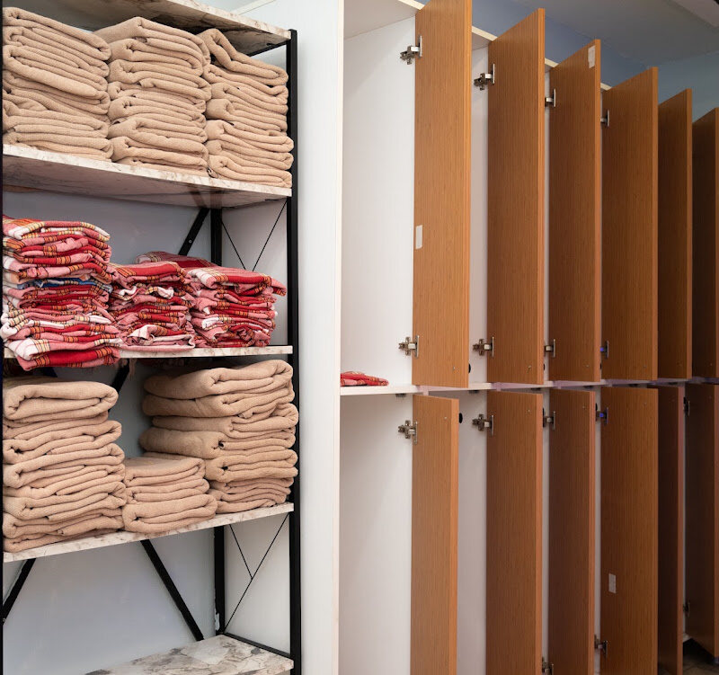 Shelves stacked with folded towels and peştemals beside wooden changing cabins.