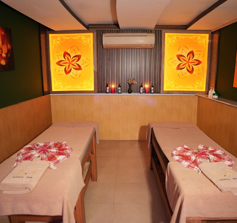 Private treatment room with two massage beds side by side under warm backlit panels.
