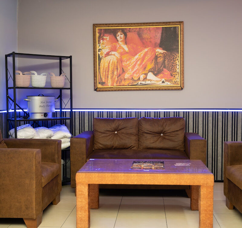 Seating area with leather sofas, a framed painting and a shelf of rolled towels.