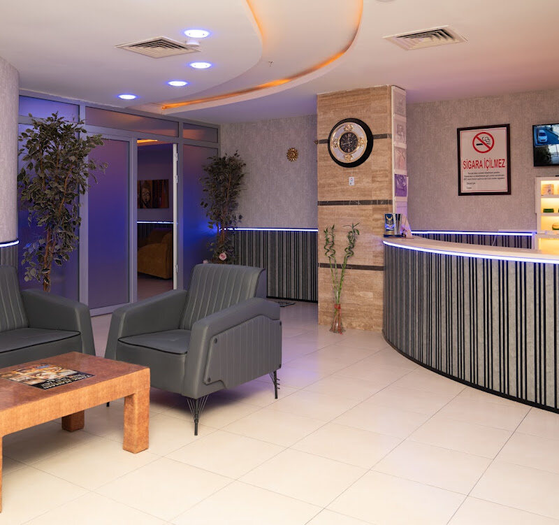 Curved reception desk with armchairs and plants at the entrance.